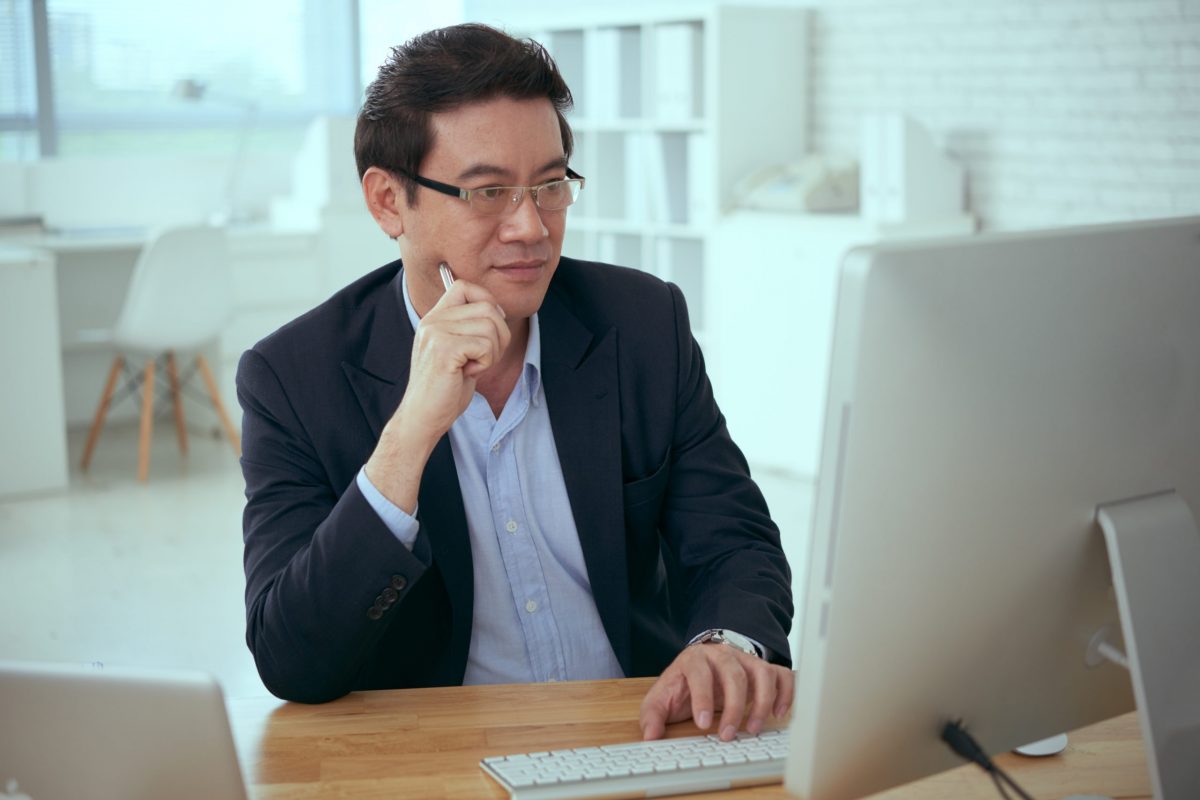 Mature Asian businessman working on computer in office